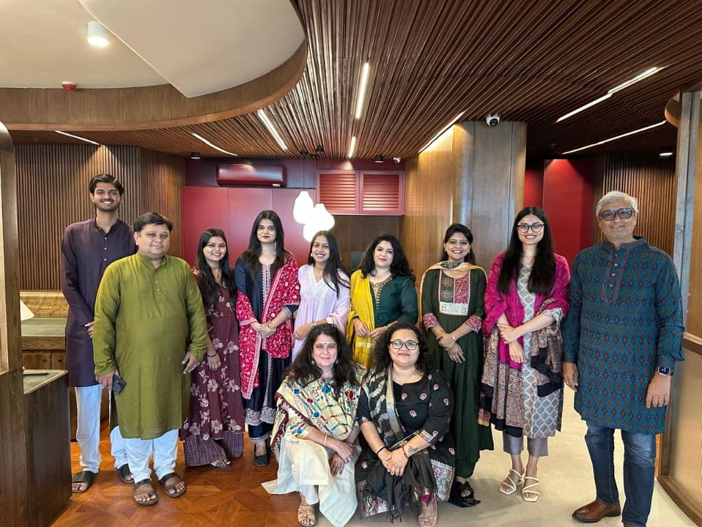 Red Envelope Consultants team together in traditional attire in the office, smiling at the camera.