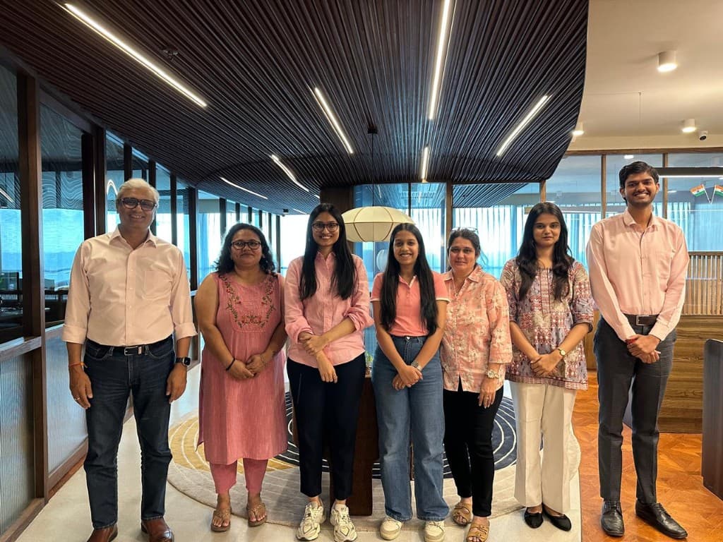 Team members in coordinated pink attire standing together in a modern office lobby.